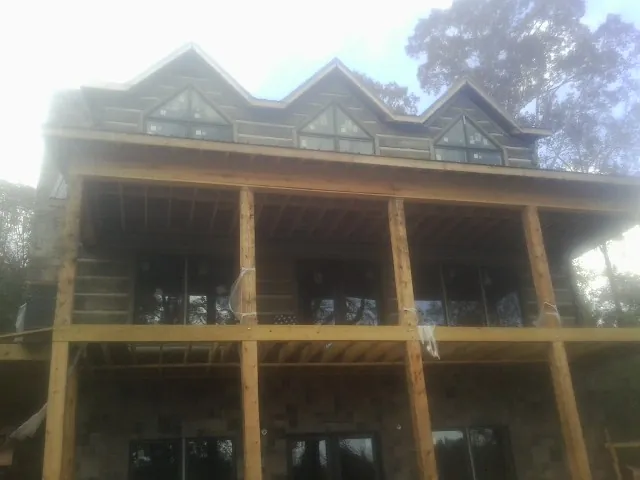 Dormers and porch framing on a large log home under construction — Roof Coating work by our crew in Glade Valley