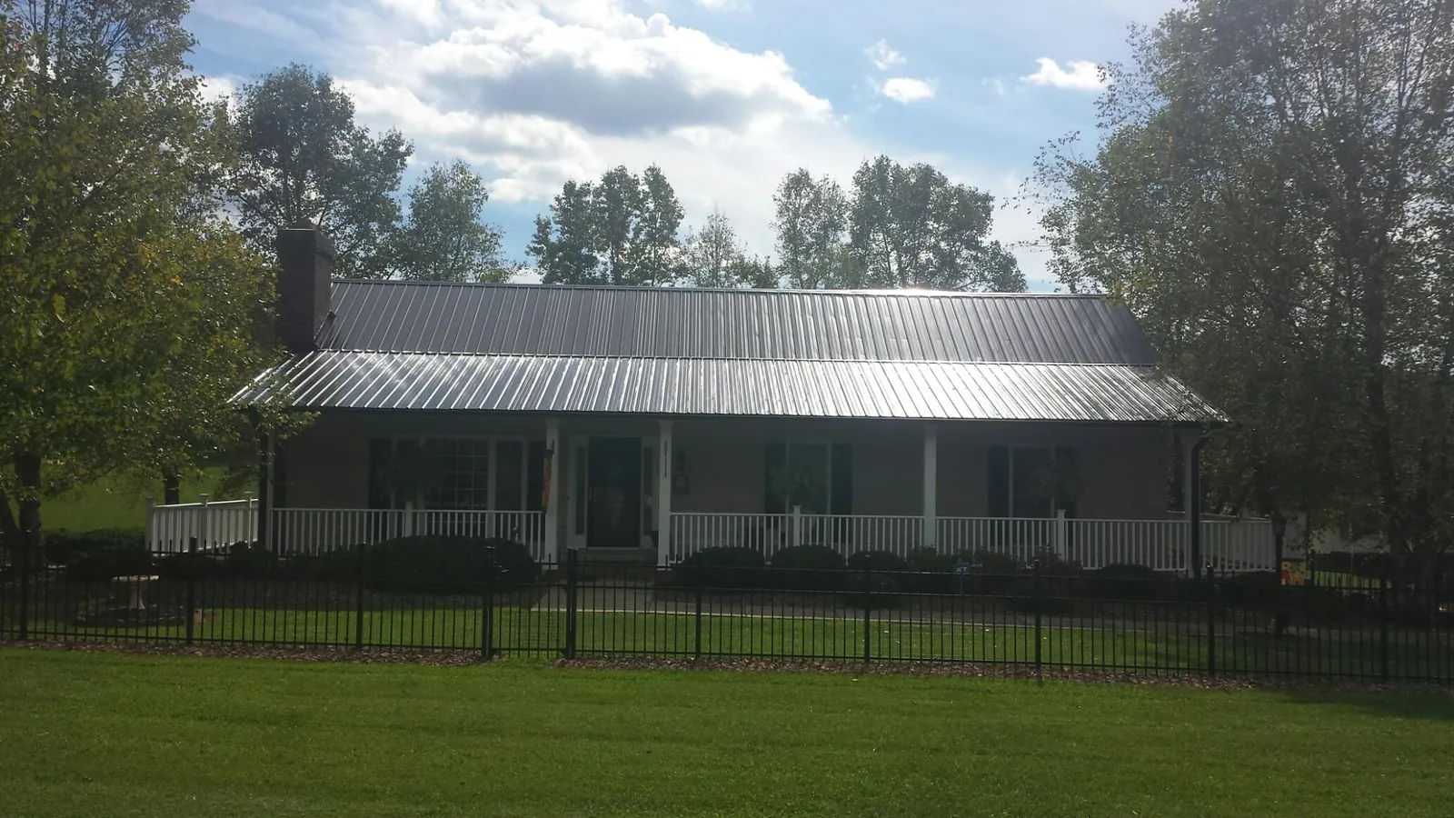 Gray metal roof on a brick ranch with a full width front porch — Gutter Guard Installation work by our crew in Glade Valley