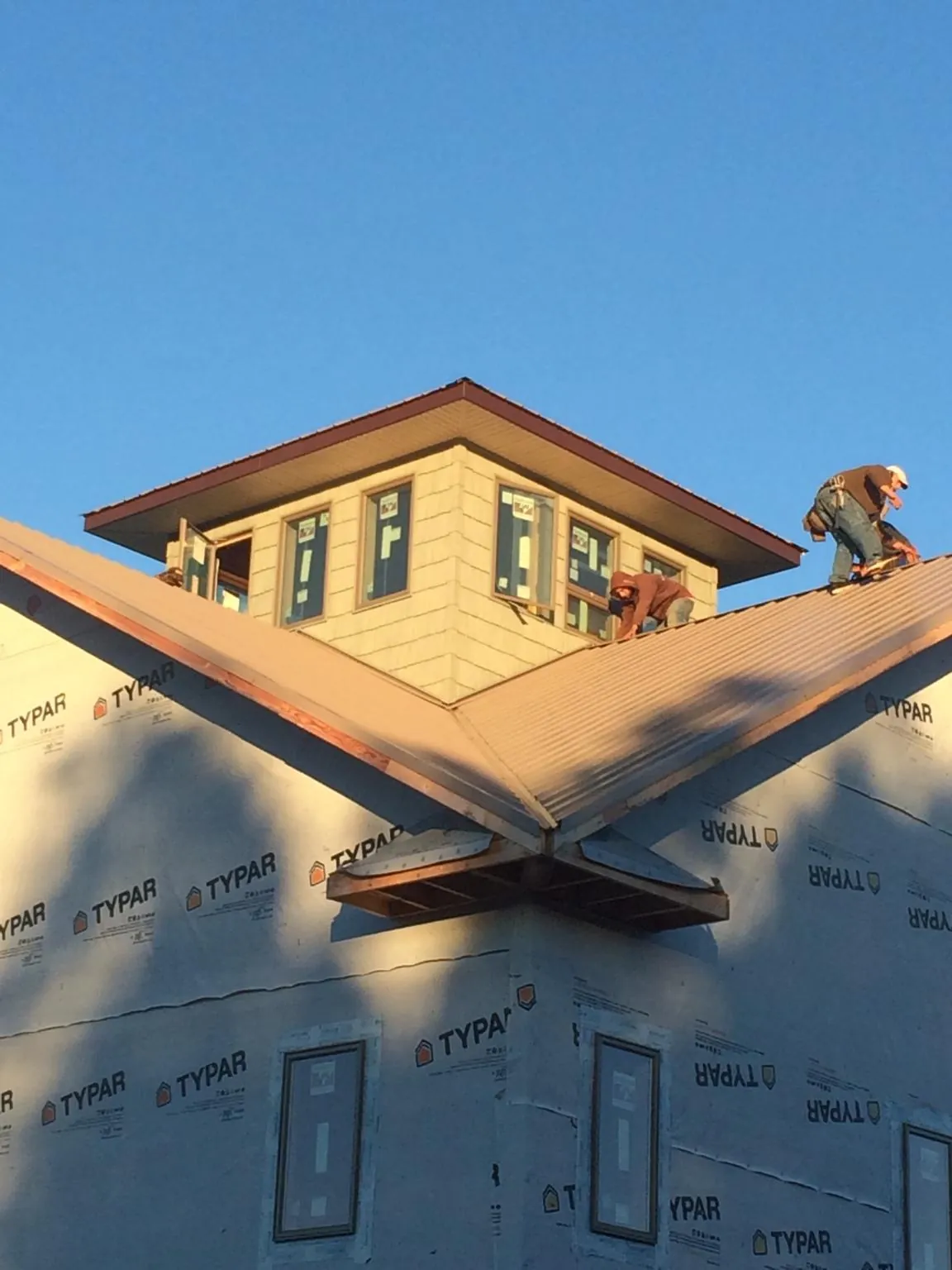 Roofers working around a rooftop cupola on a new metal roof at sunset — Roof Waterproofing in Glade Valley by Roofing Brothers